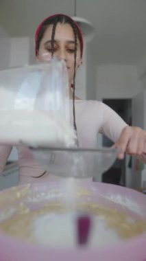 Genç bir kadın pişirme sürecinin tadını çıkarırken ustalıkla şekeri karıştırıyor.