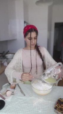 Sıcak ve rahat bir mutfak sahnesi. Rahat kıyafetler giymiş genç bir kadın ustalıkla lezzetli yemekler hazırlıyor.