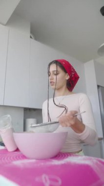 Genç bir kadın rahat mutfağında hamuru enfes ikramlara hazırlamak için ustaca hazırlıyor.