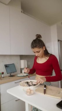 Genç bir kadın şık bir mutfakta zevkle lezzetli yemekler pişiriyor, mutfak yeteneklerini sergiliyor.