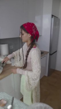 Genç bir kadın şık bir mutfakta zevkle yemek hazırlıyor. Yaratıcılık ve aşçılık becerileri sergiliyor..