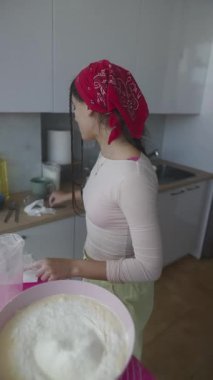 Mutlulukla ve neşeyle karıştıran bir kadın modern bir mutfakta, enfes pişirme sanatını benimsiyor.