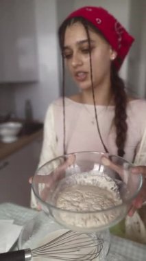 Genç bir kadın, pişirme, sergilenen etkileyici un karıştırma teknikleri için çeşitli malzemeler hazırlıyor.