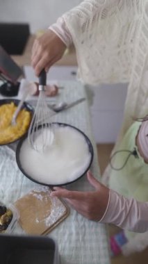 Mutfak malzemeleri ve mutfak malzemeleriyle çevrili bir kasede enerji dolu bir şekilde karışımı çırpıyor.