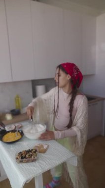 Bir kadın zarif bir şekilde tatlısını hazırlar. Güneşli bir mutfakta krema çırpar. Mutfak yeteneklerini sergiler..