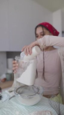 Neşeli ve canlı bir pişirme sahnesinde genç bir kadın, parlak bir mutfakta malzemelerini zevkle hazırlıyor.