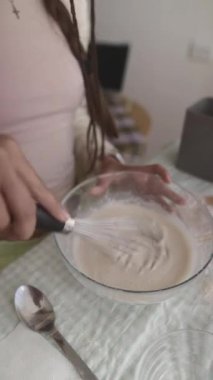 Bir insan evde yaratıcılığını göstermek için çeşitli malzemeleri bir kasede coşkuyla karıştırır.