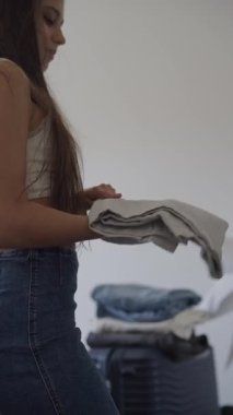Çok güzel minimalist bir yatak odasında, genç bir kadın çamaşırlarını özenle katlıyor ve düzenliyor.