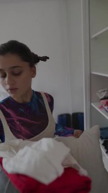 Genç bir birey çamaşırlarını titizlikle parlak, şık ve davetkar bir ortamda düzenliyor.