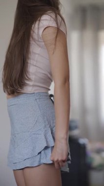 Tarz sahibi genç bir kadın moda kıyafetlerini büyük bir aynanın önünde modelliyor, modern moda eğilimlerini sergiliyor.