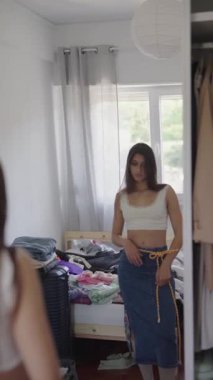 Modaya uygun bir kadın şık kıyafetini aynanın önünde sergiliyor, zarafetini sergiliyor.