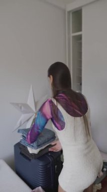 Zevkli ve şık bir yatak odası ortamında, bir insan düzenli bir şekilde elbiselerini düzenler ve düzenler.