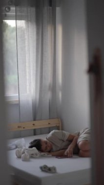 Güzel, huzurlu bir an, bir çocuğun mutlu bir şekilde yatakta dinlendiği aydınlık, güneşli bir yatak odasında yakalanır.