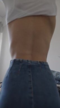 Yetenekli bir model şık kıyafetlerini parlak ve havadar bir odada değiştirir, modaya uygun kot pantolon ve gündelik görünüş giyer.