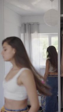 Işıl ışıl bir odada, şık bir model çeşitli modaya uygun giysiler sergiliyor, yansımaları ve stili vurguluyor