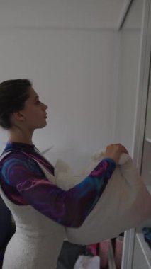 Şık bir kadın çeşitli giyim eşyaları, modern moda ve ev dekorasyonu gibi şeyleri düzenler.
