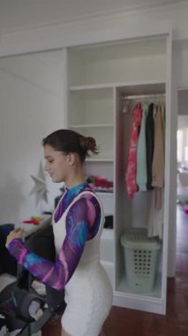 Bir kadın modern odasında şık bir kıyafet hazırlıyor, moda tercihlerini zekice sergiliyor.