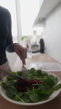 Bir insan parlak mutfak ortamında canlı ıspanak ve pancar kullanarak taze ve renkli bir salata hazırlar.
