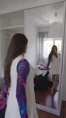 Şık ve şık bir birey, kendine güvenen parlak ve estetik bir yatak odasında modaya uygun bir kıyafet modeller.