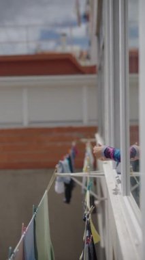 Güneşli güzel bir günde, genç bir kadın mutlu bir şekilde dışarıda renkli çamaşırlarını asıyor, canlı bir atmosferi kucaklıyor.