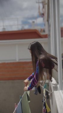 Uzun saçlı genç bir kadın, parlak bir odada konteynırla etkileşime girer ve günlük hayatın bir anını yakalar..