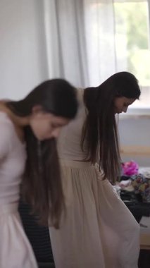 Uzun, dalgalı saçlı genç bir dansçı zarif bir şekilde aynanın önünde poz veriyor, zarafetini ve zarafetini sergiliyor.