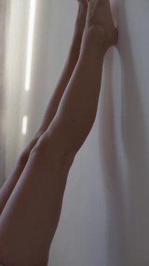 Huzurlu bir sahne, yükselmiş bacakları bir duvara yaslıyor, huzur ve rahatlama yayıyor..