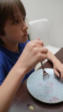 Genç bir çocuk yemeğinin tadını çıkarmaya odaklanır. Yemekten gelen saf mutluluğu gösterir.