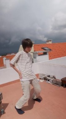 Genç ve yetenekli bir dansçı etkileyici dans figürlerini dramatik ve bulutlu bir arkaplanda sergiliyor.