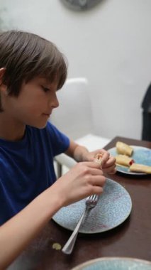 Genç bir çocuk lezzetli atıştırmalığının tadını çıkartıyor, büyük bir zevkle yemeğinin tadını çıkarmaya odaklanıyor.