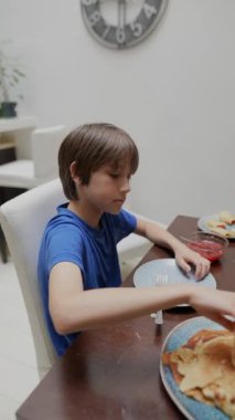 Genç bir çocuk, parlak ve modern bir mutfak ortamında jöleli leziz kreplere bayılıyor.