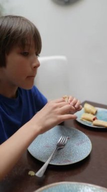 Genç bir çocuk, yemek masasında lezzetli atıştırmalıklardan hoşlanır. Sıcak ve neşeli bir atmosferde yakalanır.