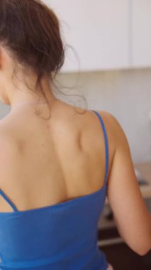 Genç bir kadın, modern bir mutfakta, canlı renkler ve rahat bir atmosfer sergileyerek ustalıkla yemek hazırlıyor.