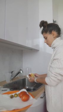 Parlak bir mutfakta, bir kadın ustalıkla taze sebzeleri soyar, aşçılık yeteneklerini ve sağlıklı beslenme yeteneklerini sergiler.