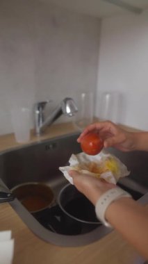 Bir insan mutfak lavabosunda canlı, taze domatesleri yıkıyor ve onları lezzetli bir yemek için hazırlıyor.