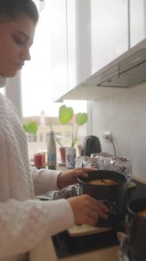 Bir kadın, modern mutfağında lezzetli pişmiş yiyecekler hazırlarken ustalıkla yemek pişirme sanatını benimsiyor.