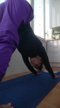 İlham verici yoga güzel bir şekilde gücünü, esnekliğini ve parlak bir ev ortamında odaklanmayı gösteriyor.
