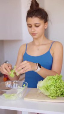 Bir kadın canlı bir salata için titizlikle taze marul hazırlıyor. Sağlıklı yemek alışkanlıklarını gösteriyor.