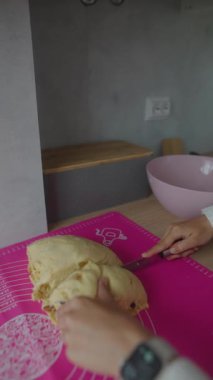 Bu dizide, hamuru pembe bir hasırın üzerinde kesme ve hazırlama sürecinin ayrıntılı süreci yer alıyor, fırın sanatını ön plana çıkarıyor.