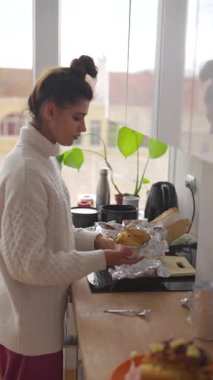 Rahat bir kazak giymiş bir kadın aydınlık ve modern bir mutfak alanında yemek hazırlamakla meşgul.