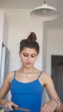 Genç bir kadın canlı ve taze bir salata hazırlıyor. Parlak, havadar ve modern bir mutfak ortamında.