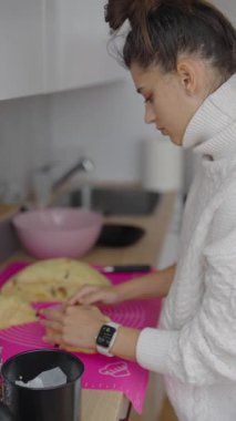 Parlak, modern bir mutfak alanında genç bir kadın özenle hamur yoğurma işine odaklanır.