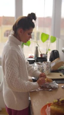 Bir kadın, davetkar mutfağında sıcak ve rahat bir sabah geçirir. Taze pişmiş yiyecekler hazırlar ve sunar.