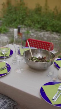 Taze salata, içecek ve zarif çiçek aksanıyla süslenmiş güzel bir açık hava yemek masası.