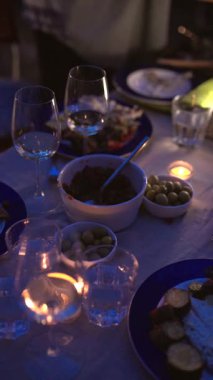 Güzel düzenlenmiş tabaklar ve yumuşak mum ışığı ile samimi bir akşam yemeği ortamı oluşturur..