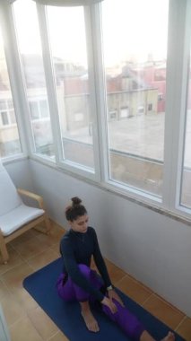 Bir çocuk, esnek ve yetenekli olduğunu etkileyici bir yoga pozuyla, kapalı bir ortamda gösterir..