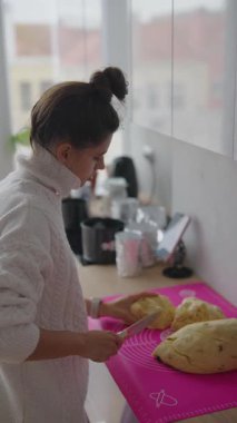 Bir kadın, canlı renklerle dolu parlak, modern bir mutfakta ustalıkla ve ustalıkla lezzetli bir ekmek hazırlar.