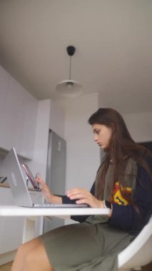 Kendini işine adamış ve odaklanmış genç bir kadın modern bir çalışma ortamında laptopuyla aktif olarak meşgul.