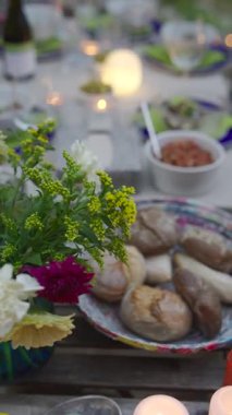 Enfes bir açık hava yemek seti lezzetli ekmekler, canlı çiçekler ve şık, zarif sofra takımı sergiler.