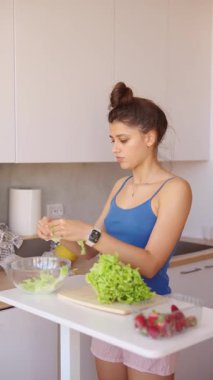 Genç bir birey modern, çağdaş bir mutfak ortamında taze salata malzemelerini ustalıkla hazırlıyor.